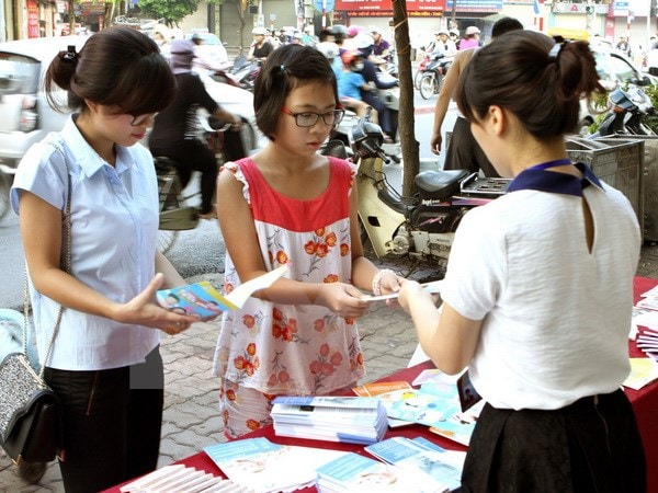 Cấp phát tờ rơi tuyên truyền chăm sóc sức khỏe sinh sản vị thành niên trên các tuyến phố. (Ảnh: Dương Ngọc/TTXVN)