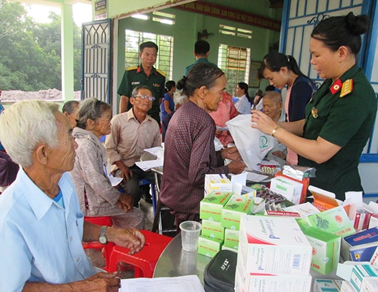 Cán bộ, chiến sĩ lực lượng vũ trang huyện Duy Xuyên khám bệnh, cấp thuốc miễn phí cho gia đình chính sách. Ảnh: HOÀI NHI