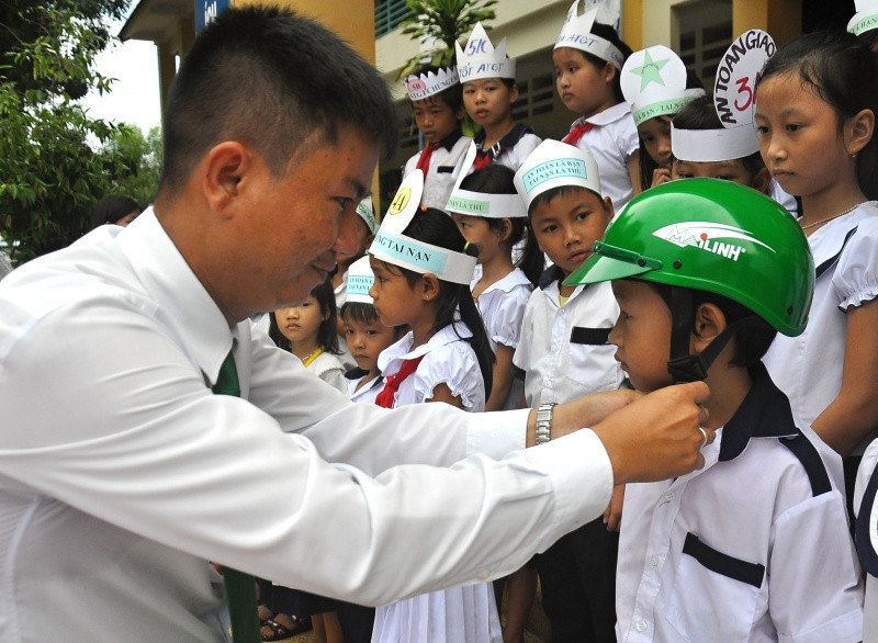 Đại diện taxi Mai Linh Tam Kỳ trao tặng mũ bảo hiểm cho học sinh. Ảnh: V.A