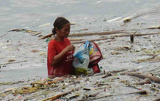 Một phụ nữ Philippines cố thu nhặt những gì còn sót khi bão Sarika đi qua .ảnh: AP