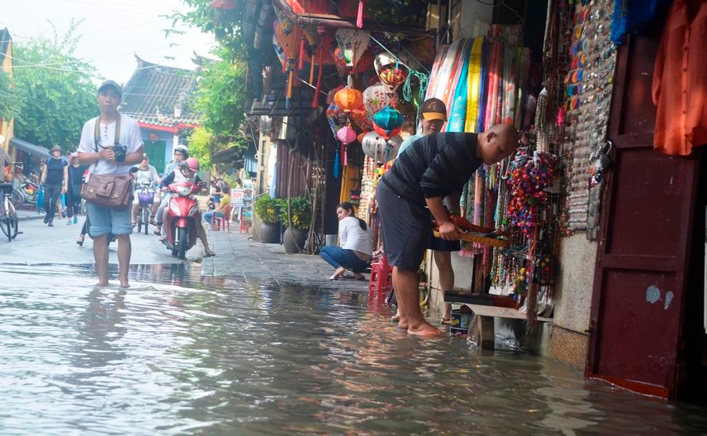 Tại một số tuyến đường nước đang mấp mé, người dân di chuyển đồ đạc, tài sản đến nơi cao ráo hơn. Ảnh: XUÂN THỌ