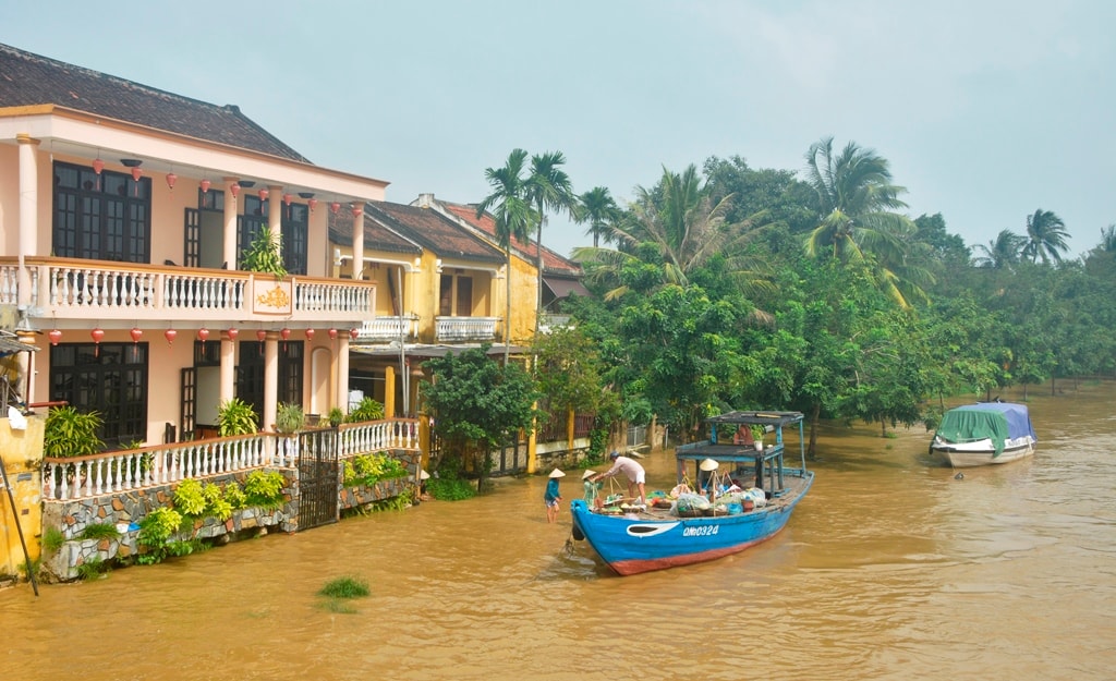 Những người bán hàng rong phải dùng tàu để di chuyển gánh hàng vì nước lũ dâng cao. Ảnh: XUÂN THỌ