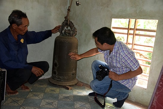 Ông Hòe chỉ những chữ Hán in trên chuông đồng. Ảnh: THANH THẮNG