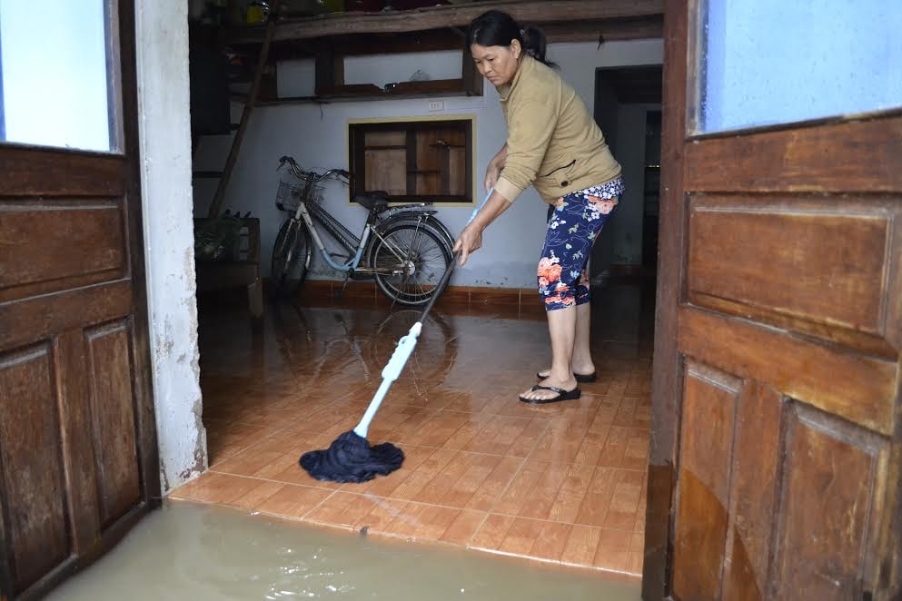 Người dân thị trấn Ái Nghĩa lau chùi nền nhà khi nước đang rút dần. 