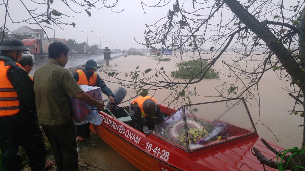 Hài cốt của liệt sỹ Võ Đức Sinh (hy sinh ngày 18.5.1979, quê xã Duy Hòa) phải dùng canô di chuyển do nước lũ làm ngập tuyến đường từ Quốc lộ 1 lên Nghĩa trang liệt sỹ huyện Duy Xuyên. Ảnh: XUÂN THỌ