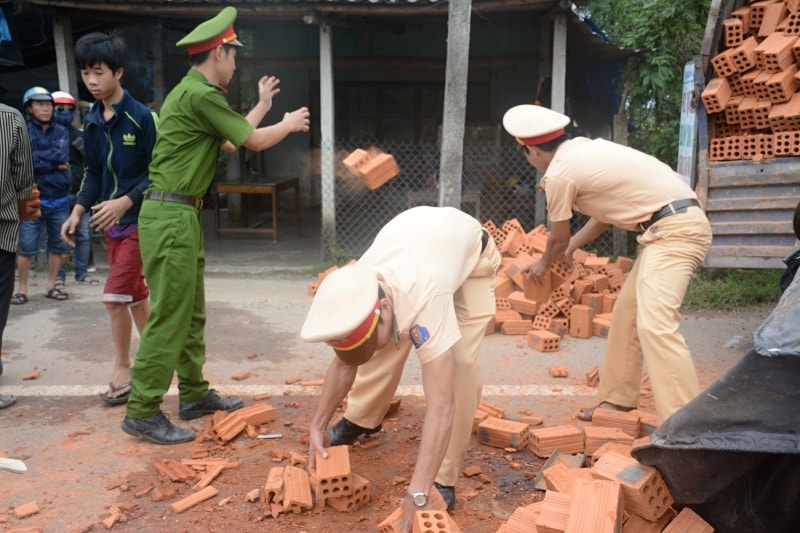 Công an huyện Núi Thành cùng người dân dọn dẹp số gạch. Ảnh: HỒNG BẰNG