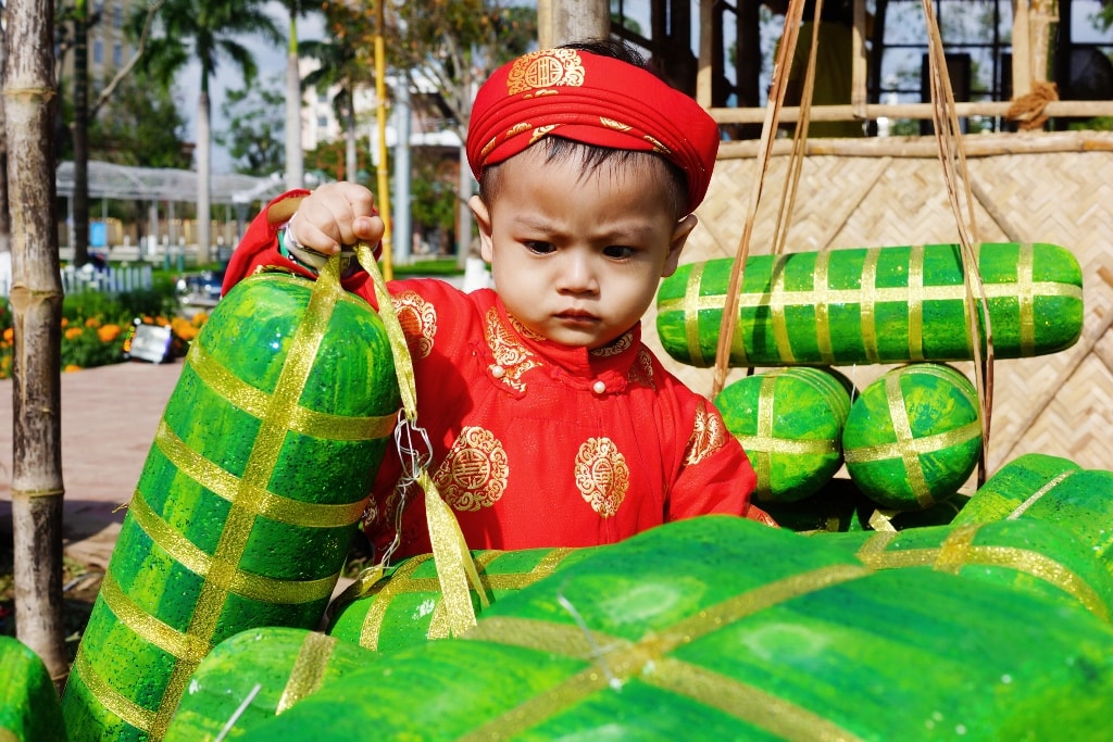 Một em nhỏ thích thú với mô hình bánh tét được trưng bày phục vụ tham quan trong ngày tết cổ truyền.