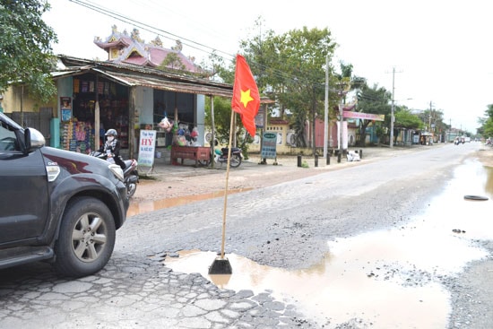 Người dân cắm cờ Tổ quốc trên “ổ gà” rất phản cảm.  Ảnh: S.C