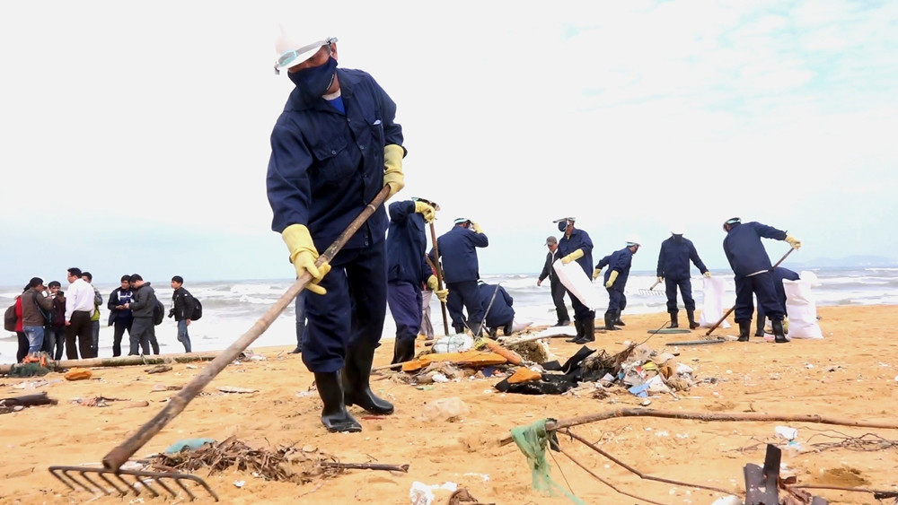 Hơn 20 công nhân công ty Môi trường đô thị Quảng Nam thực hiện thu gom dầu vón cục, rác thải trôi dạt vào bở biển Biển Rạng. ẢNH: ĐẠO HIỀN