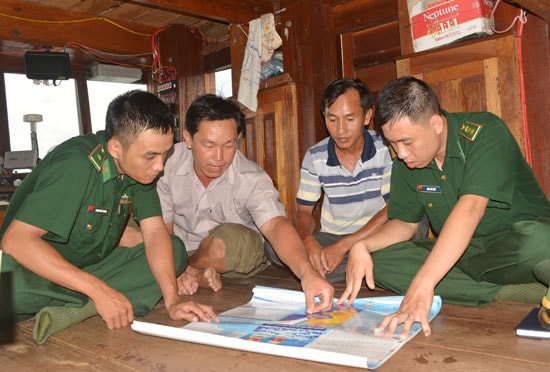 Các chiến sĩ Đồn Biên phòng Cửa khẩu cảng Kỳ Hà thông tin về chủ quyền vùng biển cho ngư dân trước ngày ra khơi. Ảnh: ALĂNG NGƯỚC