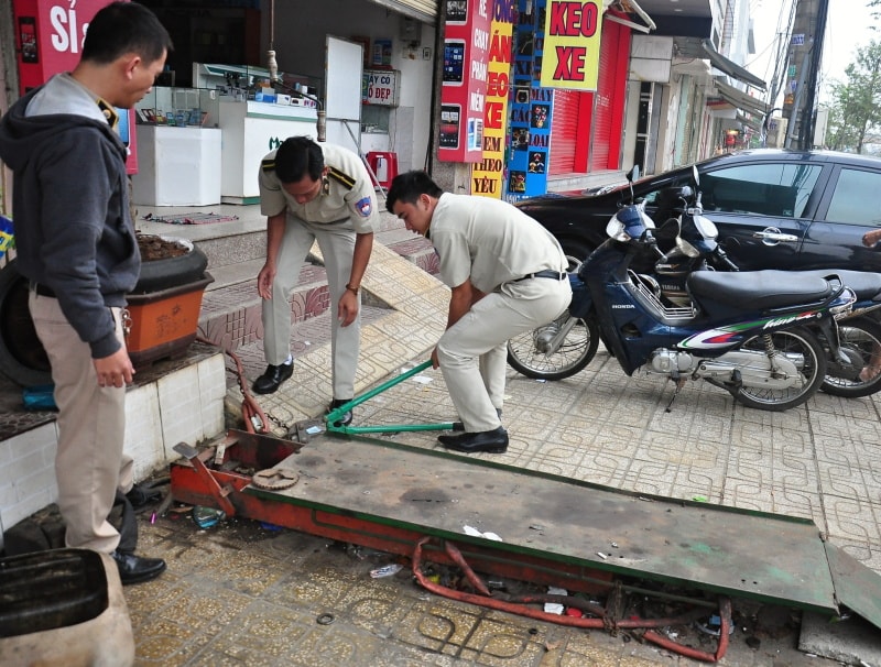 Tháo dỡ các vật dụng cố định lấn chiếm vỉa hè . Ảnh: VINH ANH