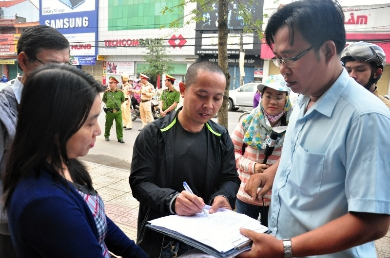 Người dân ký vào biên bản tạm giữ phương tiện. Ảnh: VINH ANH