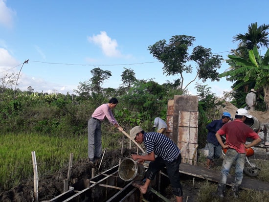 Anh Lê Trung Tấn (mặc áo trắng bên trái) giám sát công trình xây dựng kênh mương nội đồng tại Cẩm Kim. Ảnh: L.H