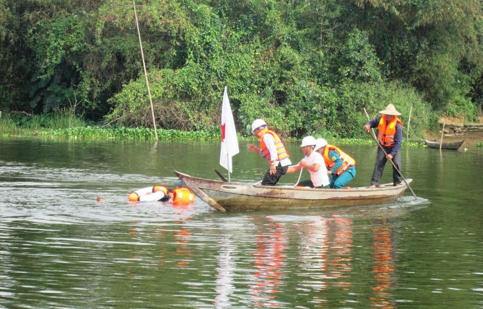 Các thành viên đội xung kích quăng phao tròn cho người bị đuối nước trên nhánh sông Thu Bồn.