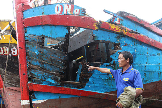 Ngư dân Nguyễn Hữu Mười bên con tàu đã bị đâm hư hỏng nặng. Ảnh: NGUYỄN THÀNH