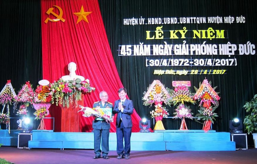- Ảnh 3: Ông Nguyễn Như Công - Chủ tịch UBND huyện Hiệp Đức tặng hoa cho Anh hùng LLVTND Trần Văn Thắng. 
