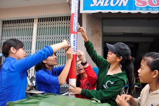 Đoàn viên thanh niên bóc, xé quảng cáo trên các tuyến đường TP.Tam Kỳ. Ảnh: VINH ANH