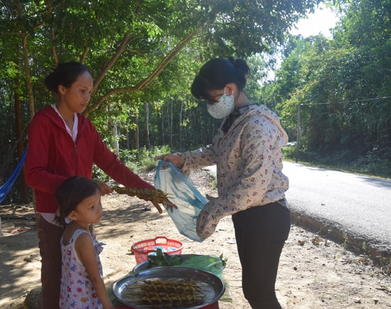 Chị Bông (bìa trái) đang bán cá bống đã được nướng thơm lừng cho du khách. Ảnh: THẮNG DƯƠNG