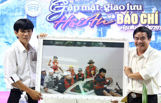 Ông Nguyễn Sự (trái) nhận quà là bức ảnh chụp trên chuyến kiểm tra tình hình lũ lụt cùng các nhà báo, do đồng nghiệp Báo Lao động tặng dịp ông nghỉ hưu. Ảnh: H.X.H