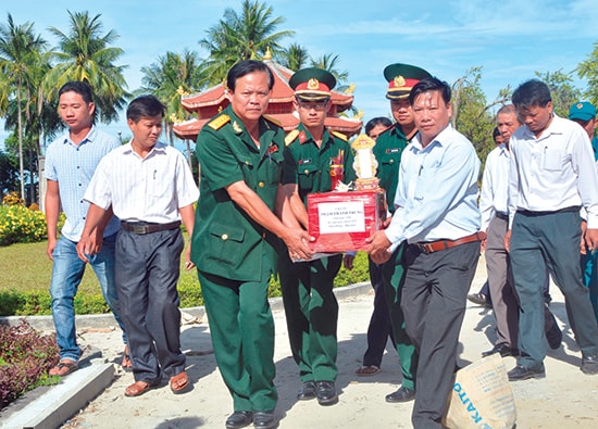 Đại tá Nguyễn Quang Ngọc - thành viên Ban liên lạc Trung đoàn 96 (bên trái) đưa hài cốt đồng đội về nơi an táng trên đất mẹ Quảng Nam. Ảnh: THÀNH CÔNG