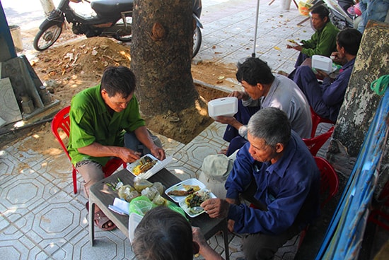 Nhà xa, nên các công nhân đội chỉnh trang đô thị ăn vội bữa cơm trưa ngay trên công trường. “Cơm nước xong xuôi, tranh thủ nghỉ ngơi chút xíu rồi đi làm luôn. Đội mấy chú làm công việc lót gạch vỉa hè đã hơn tháng ni rồi” - ông Trần Sỹ, ở thôn An Hòa (xã Tam An, huyện Phú Ninh) cho biết.