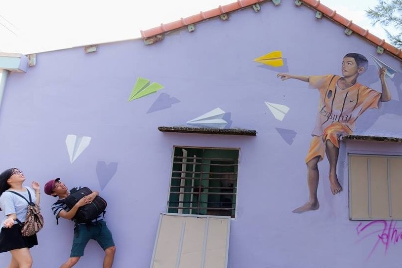 Tourists and one of the paintings in Tam Thanh mural village (Photo: Nguyen Ngoc Phap)