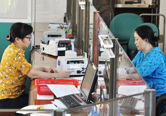 Ký kết phối hợp thu ngân sách Nhà nước qua ngân hàng là bước đi thực hiện rõ chủ trương thanh toán không dùng tiền mặt của Chính phủ.  Trong ảnh: Cán bộ Kho bạc Nhà nước thành phố hướng dẫn người dân nộp thuế.