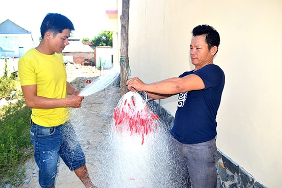 Ngư dân Huỳnh Văn Mười (phải) sửa sang vàng lưới ghẹ để chuyển sang đi biển ven bờ. Ảnh: Q.VIỆT