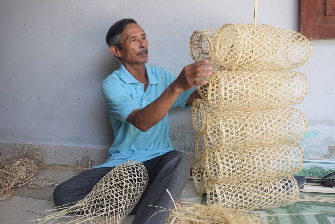 Ông Nguyễn Sự (59 tuổi), bên những chiếc lờ vừa mới đan xong - Ảnh: THANH THẮNG.