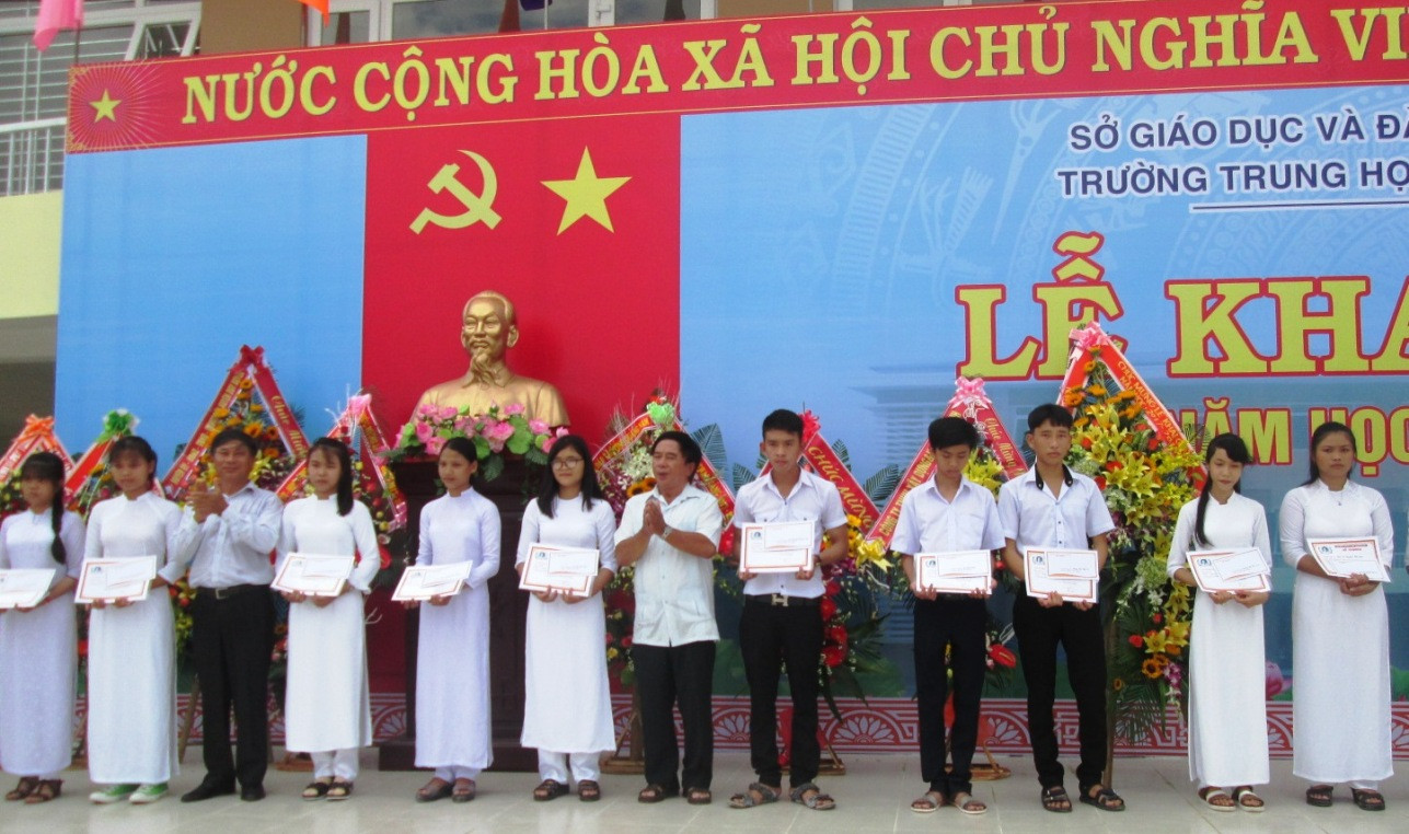 Đại diện gia đình ông Hồ Nghinh trao học bổng cho các em học sinh tại lễ khai giảng. Ảnh: VĂN SỰ          