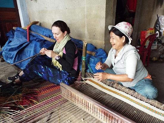 A visitor experiences sedge mat making with a local resident via Cultures Connect