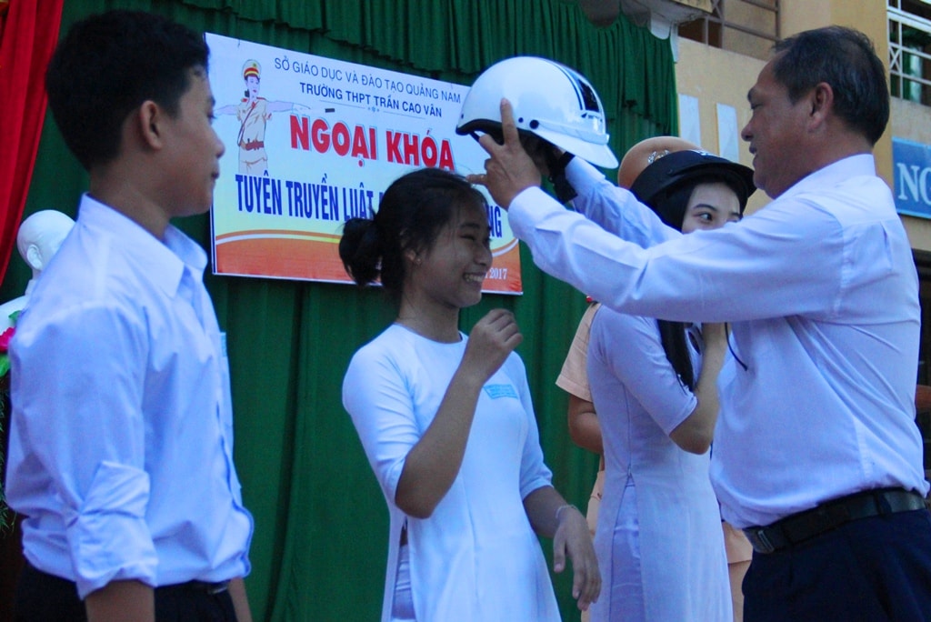 Đại diện lãnh đạo nhà trường trao phần thưởng mũ bảo hiểm cho các em học sinh trả lời chính xác câu hỏi đố vui tại buổi ngoại khóa. Ảnh: ALĂNG NGƯỚC