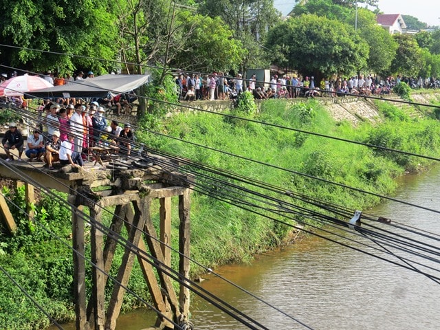 Bất chấp nguy hiểm, người dân đổ xô leo lên mố cầu cũ để xem tìm kiếm thi thể cô gái trẻ. Ảnh: TRIÊU NHAN