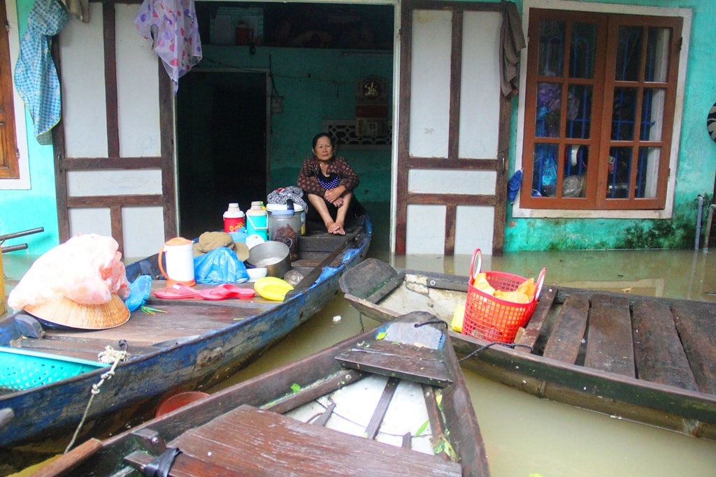 Bà Trần Thị Hiền ngồi co ro trên chiếc thuyền giữa ngôi nhà bị ngập sâu trong nước lũ. Ảnh: A.N