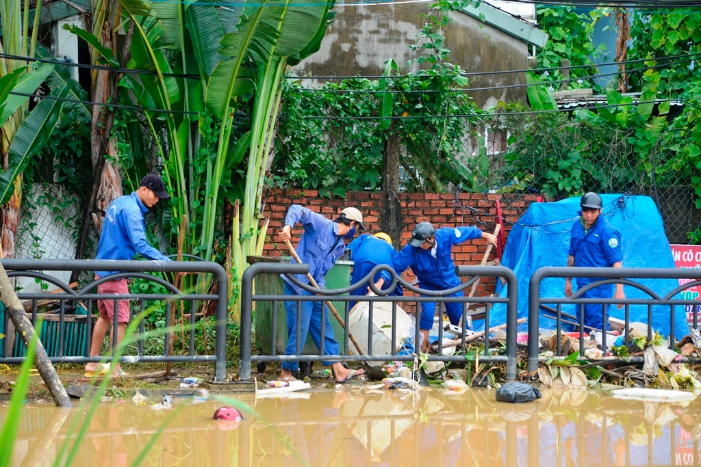 Công nhân Công ty CP Công tình công cộng Hội An giúp dân dọn dẹp tại những nơi có nhiều rác. Ảnh: XUÂN THỌ