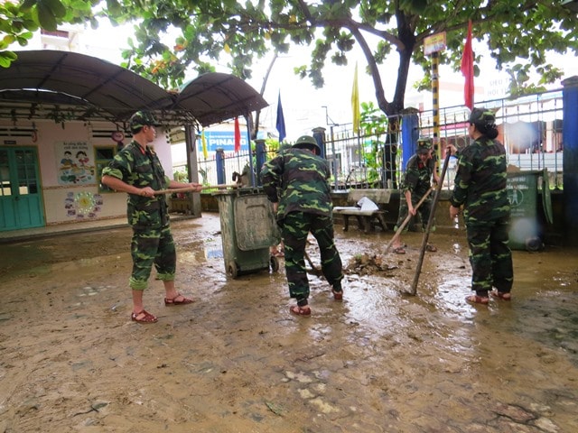 Lực lượng cán bộ, chiến sĩ Ban chỉ huy Quân sự huyện giúp trường Mẫu giáo Ái Nghĩa dọn vệ sinh sau lũ. Ảnh: HOÀNG LIÊN