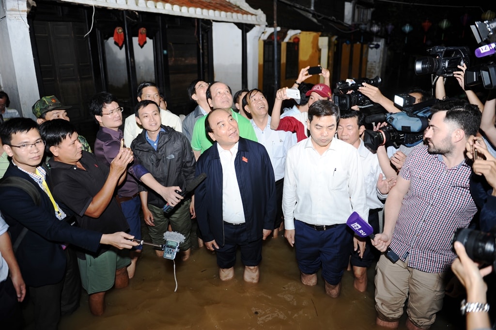 Tại đường Nguyễn Thị Minh Khai còn ngập nước, Thủ tướng rướng người hỏi thăm tình hình của nhà dân. Ảnh: HẢI THỌ