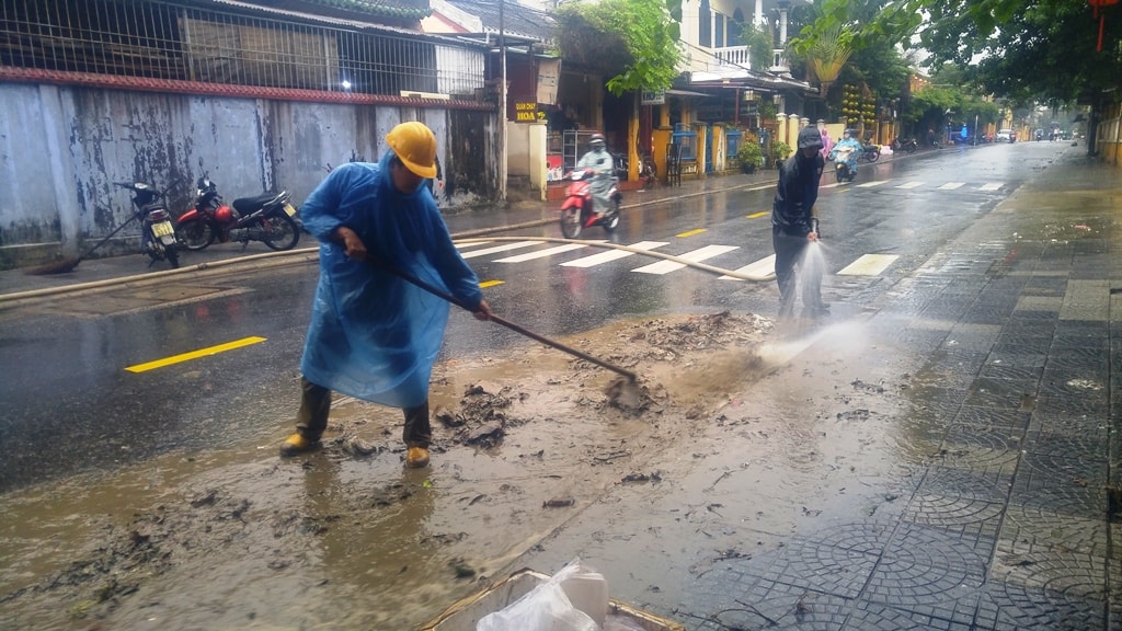 Công nhân Công ty CP Công tình công cộng Hội An xịt rửa bùn đất. Ảnh: XUÂN THỌ