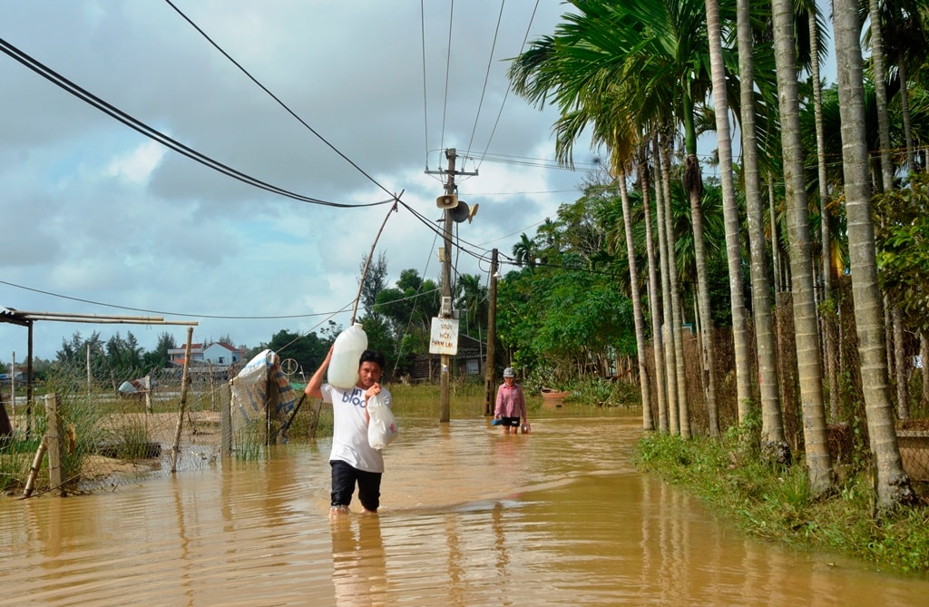 Ông Nguyễn Sáu - Chủ tịch UBND xã Duy Vinh cho biết hiện xã này đang có 5 thôn bị cô lập, đó là các thôn Đông Bình, Hà Mỹ, Hà Thuận, Trà Nam và Trà Đông do nằm ở vùng thấp. Trong ảnh là anh Trung ở thôn Đông Bình lội nước để mang đồ ăn và nước ngọt từ trung tâm xã về. Ảnh: XUÂN THỌ