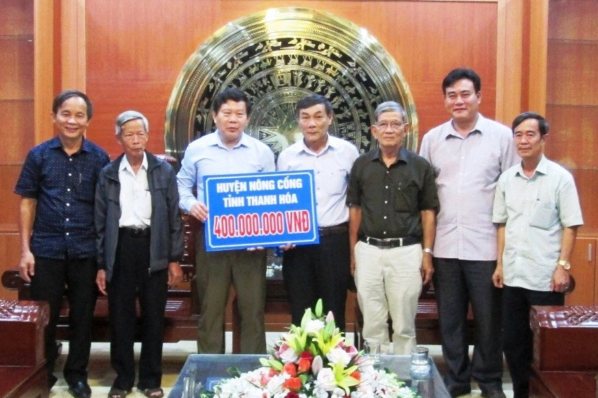 Lãnh đạo huyện Nông Cống trao tượng trưng số tiền hỗ trợ 400 triệu đồng cho huyện Duy Xuyên.  Ảnh: THÀNH SỰ