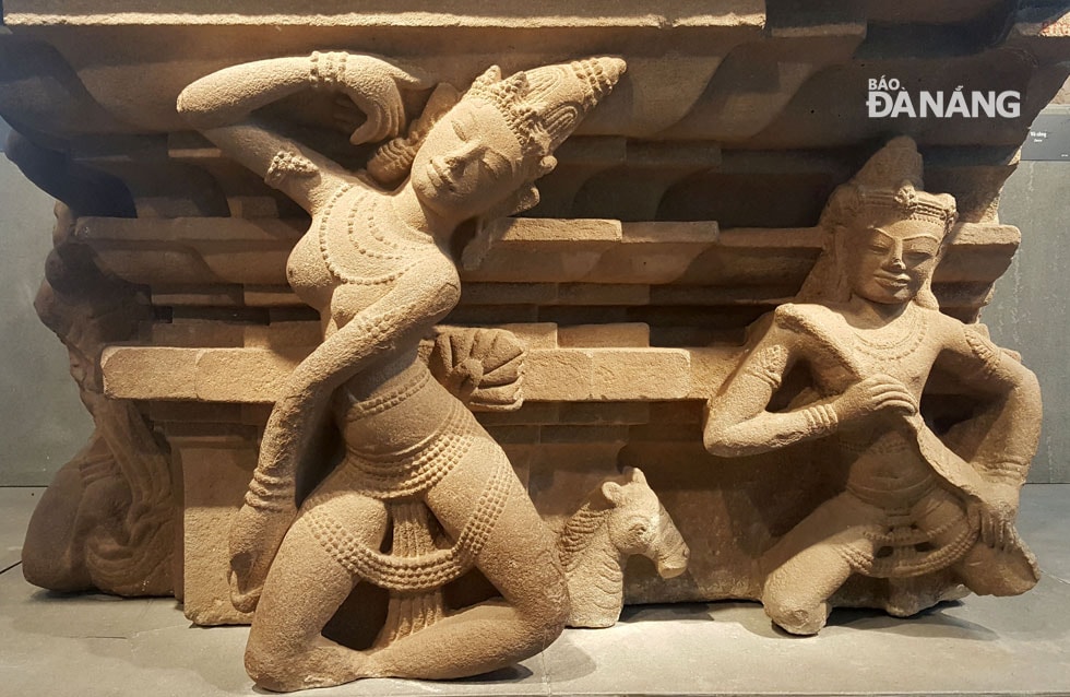Apsara- là kiệt tác trong nghệ thuật điêu khắc Chăm, tác phẩm thể hiện hai vũ nữ Apsara trong tư thế múa uốn cong duyên dáng. Các vũ nữ mặc một loại váy mỏng, được nhận biết qua chiếc tà buông xuống giữa hai chân và thắt nơ ở sau lưng. Khuôn mặt toát lên vẽ đẹp dịu dàng, thuần khiết với hàng lông mày hơi cong, đôi mặt hình hạnh nhân. Trên cổ, tay và vòng eo được trang trí những chuỗi hạt ngọc chạm khắc tinh xảo. Kế bên các vũ nữ, nhạc công Gandharva đang chơi một loại nhạc cụ dây tên là tuila.