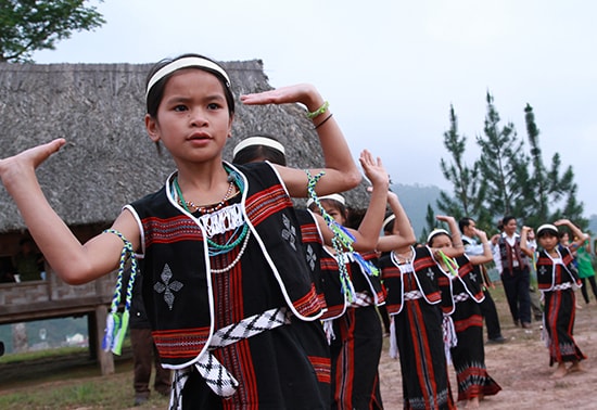 Một em bé vùng cao xúng xính trong chiếc áo thổ cẩm ngày lễ hội.