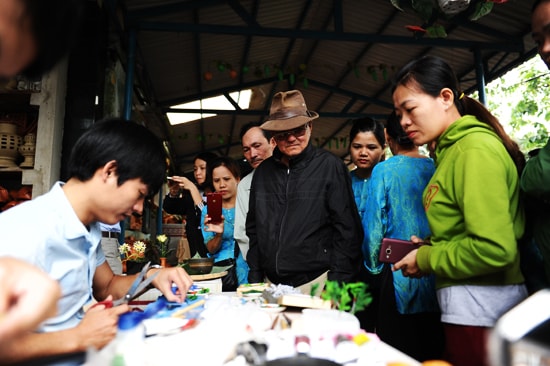 Các nghệ nhân làng gốm Thanh Hà xem 2 nghệ nhân trẻ của làng sản xuất hàng lưu niệm. Ảnh: MINH HẢI