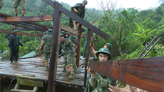Cán bộ, chiến sĩ lực lượng vũ trang tỉnh giúp dân tháo dỡ nhà cửa di dời đến nơi ở mới.