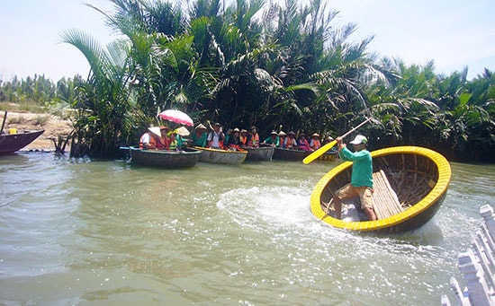 Du khách thích thú xem ngư dân lắc thúng chai khi khám phá đời sống sông nước ở rừng dừa Cẩm Thanh. Ảnh: ĐỖ HUẤN