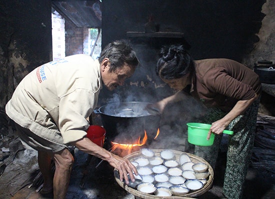 Vợ chồng chú Sự đang lấy bánh ra từ lò. Ảnh: L.T