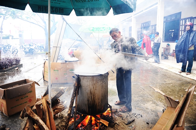 Đội mưa nấu bánh tét. Ảnh: MINH HẢI