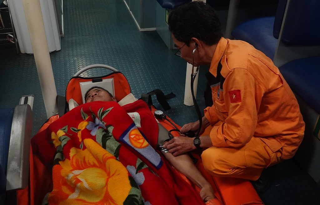 Nhân viên cứu nạn đang chăm sóc y tế cho thuyền viên người Philipines. Ảnh: XUÂN THỌ