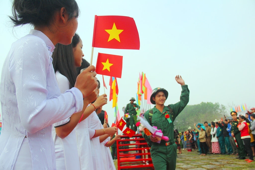 Các tân binh vẫy tay chào người thân, bạn bè sau khi bước qua cầu vinh quang. Ảnh: ALĂNG NGƯỚC