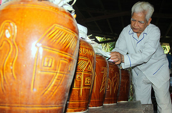 Ông Zơrâm Pháo xếp ngay ngắn từng ché rượu cần chuẩn bị bán ra thị trường. Ảnh: ALĂNG NGƯỚC